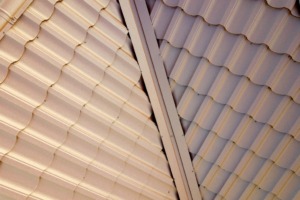 House roof surface covered with brown metal tile sheets.